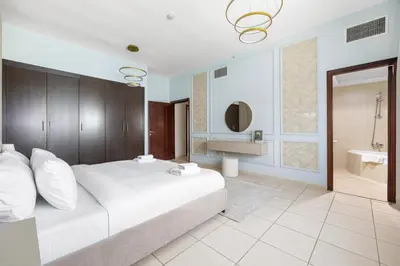 a bedroom with a large white bed and a bathroom at Spacious 3BR with Gym & Pool in Royal Residences in Dubai
