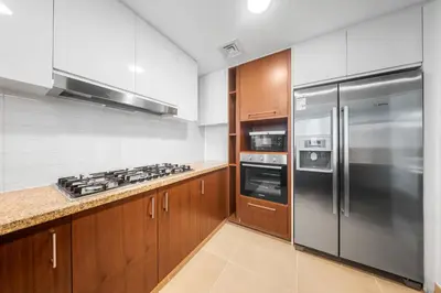 a kitchen with wooden cabinets and stainless steel appliances at Luxury 4 BR with full Burj Khalifa and Fountain View - Connected to Dubai Mall and Metro Station in Dubai