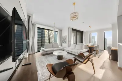a living room with a tv and a couch and chairs at Luxury 4 BR with full Burj Khalifa and Fountain View - Connected to Dubai Mall and Metro Station in Dubai