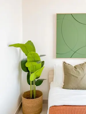 a plant in a pot next to a bed at Amberwood 2BR Haven at Dawn by Binghatti JVC in Dubai