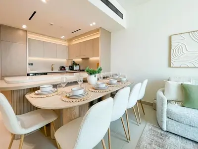 a dining room with a table and white chairs at Amberwood 2BR Haven at Dawn by Binghatti JVC in Dubai