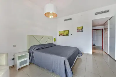 a white bedroom with a bed and a chair at Marina View Relax - Sadaf 1BR Apartment in Dubai
