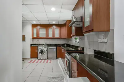 a kitchen with wooden cabinets and a washer and dryer at Marina View Relax - Sadaf 1BR Apartment in Dubai