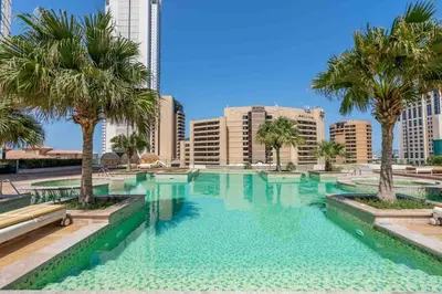 a large swimming pool with palm trees and buildings at GuestReady - 2BR l Stunning Marina Views in Dubai