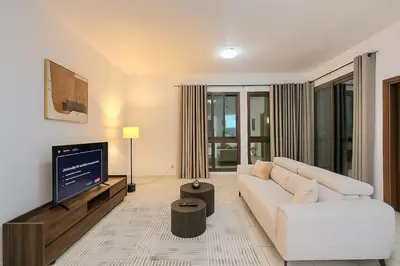 a living room with a white couch and a flat screen tv at Convenient Location in JVC Bright 1BR with Balcony in Dubai