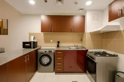 a small kitchen with a stove and a dishwasher at Convenient Location in JVC Bright 1BR with Balcony in Dubai