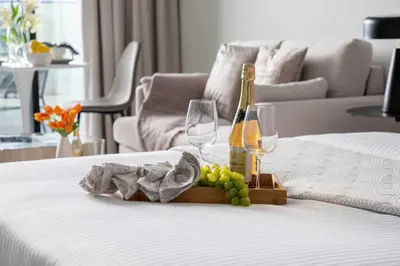 a bottle of champagne and wine glasses on a bed at Frank Porter - Al Serh Residences 11 in Dubai