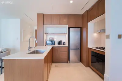 a kitchen with wooden cabinets and a stainless steel refrigerator at Lush Apartment - Private Beach Emaar - Beachfront in Dubai