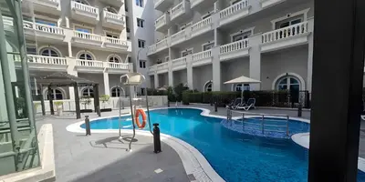 a man standing next to a swimming pool in a building at Peaceful Apartment - Cozy Interiors - 1BR in JVC in Dubai