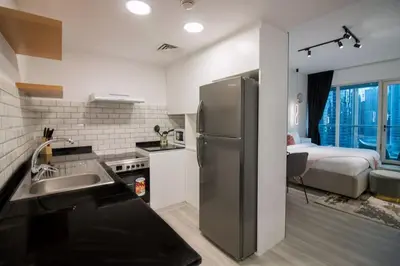 a kitchen with a stainless steel refrigerator and a bedroom at Studio at Dubai Arch 2005 in Dubai