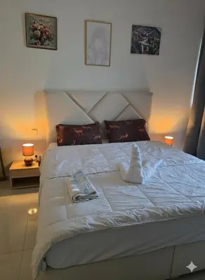a white bed with two towels on top of it at Dragon Golden Apartment 003 in Dubai