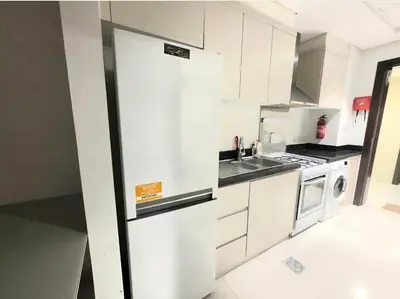 a kitchen with white cabinets and a refrigerator at Dragon Golden Apartment 003 in Dubai