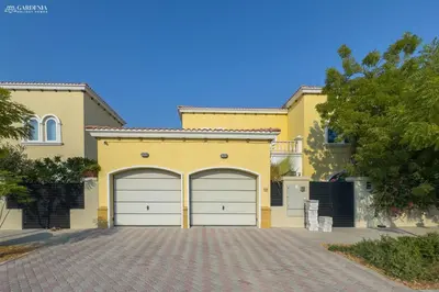 a yellow house with two garage doors in a driveway at Elite Villa in Jumeirah Park - Private Pool - 4BR in Dubai