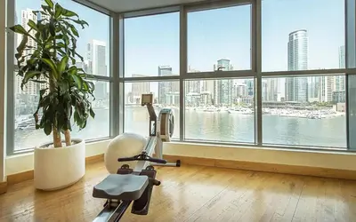 a room with a gym with a plant and windows at Chic waterfront 1 bedroom apartment, walk to beach, promenade, metro in Dubai