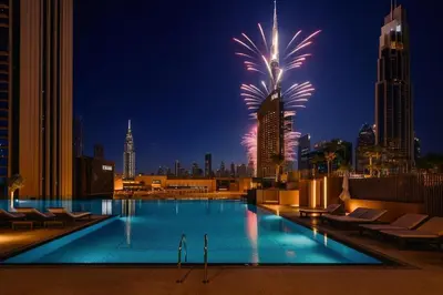 a pool with fireworks in the city at night at Downtown with Direct Access Dubai Mall & Burj Khalifa in Dubai