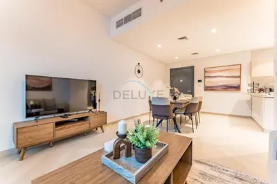 a living room with a large tv and a table at Furnished Balcony with Creek Views, Near Ras Al Khor Wildlife Sanctuary and Downtown Dubai - Wilton Park Residences 1, Sobha Hartland by Deluxe Holiday Homes in Dubai