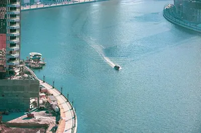 a boat in a large body of water with buildings at Contemporary Studio in Business Bay - Burj Khalifa View - Gym & Pool in Dubai