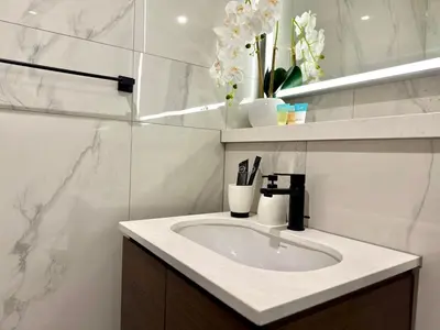 a white bathroom with a sink and flowers on a shelf at Spacious apartment with Burj Khalifa view close to Dubai mall! in Dubai