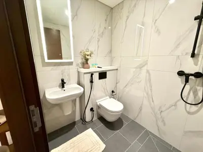 a white bathroom with a toilet and a sink at Spacious apartment with Burj Khalifa view close to Dubai mall! in Dubai