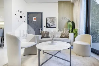 a living room with white chairs and a table at Bloomfields Classic 2Br With Private Pool Samana in Dubai