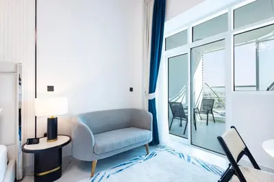 a living room with a chair and a balcony at Opalz by Danube,Dubai Science Park - Studio Apartment - Allsopp & Allsopp in Dubai