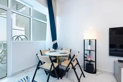 a dining room with a table and chairs and a tv at Opalz by Danube,Dubai Science Park - Studio Apartment - Allsopp & Allsopp in Dubai