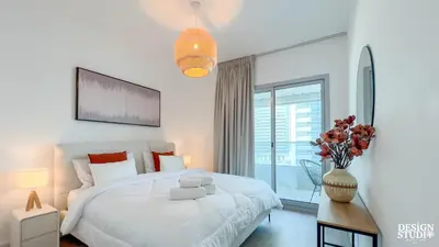a white bedroom with a bed and a vase of flowers at MARINA DIAMOND 6 by Design Studio in Dubai