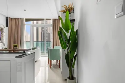 a white kitchen with a table and a plant at Modern 2BR Luxury Apartment with Downtown Dubai & Burj Khalifa Views in Dubai