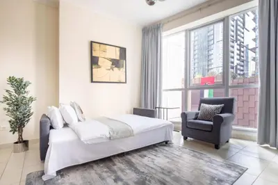 a bedroom with a bed and a chair and a window at Frank Porter - Torch Tower Marina in Dubai