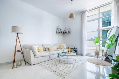 a white living room with a couch and a table at Frank Porter - Polo Residence C5 in Dubai