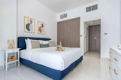 a white and blue bedroom with a large bed at Frank Porter - Polo Residence C5 in Dubai