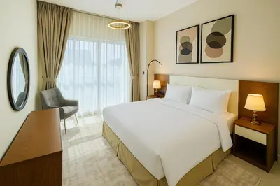 a hotel room with a large bed and a chair at Luxury Apartment Fully Furnished Jumeirah Garden City in Dubai