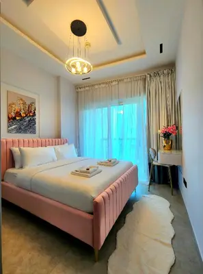 a bedroom with a pink bed and a large window at MARINA VIEW TOWER a WING in Dubai