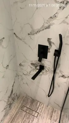 a bathroom with a white marble wall with a black plug at MARINA VIEW TOWER a WING in Dubai
