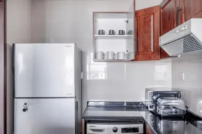 a kitchen with a white refrigerator and wooden cabinets at Blueground Icon Tower city view gym parking DXB-1332 in Dubai