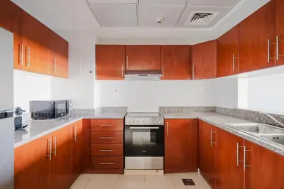 a kitchen with wooden cabinets and a stove top oven at Blueground JLT pool gym nr Marina JBR DXB-1616 in Dubai