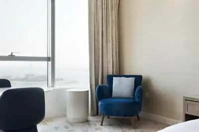 a bedroom with a blue chair and a window at Blueground The Palm Jumeirah jacuzzi nr Atlantis DXB-1708 in Dubai