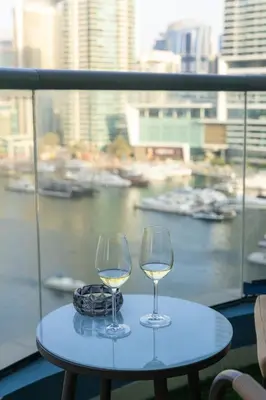 two glasses of white wine sitting on a table on a balcony at Rare apt with views of both Marina and JBR wheel in Dubai