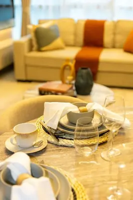 a table with plates and dishes on a table with a couch at Rare apt with views of both Marina and JBR wheel in Dubai
