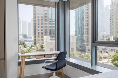 a desk and chair in a room with windows at Blueground Downtown Dubai pool nr Burj Khalifa DXB-1735 in Dubai