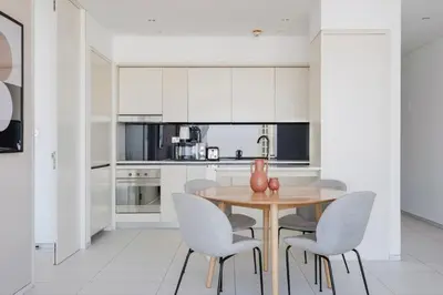 a kitchen with white cabinets and a wooden table and chairs at Blueground DIFC pool nr Dubai Mall DXB-1743 in Dubai