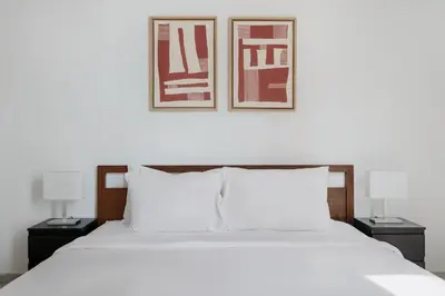 a bedroom with a white bed with two pictures on the wall at Blueground JLT pool nr Lake DXB-1747 in Dubai