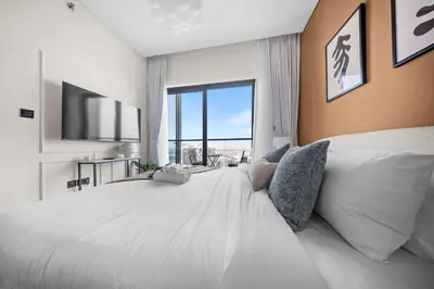 a bedroom with a large white bed with a large window at StayShort - Modern 1 Bed in Meydan Sleeps 4 in Dubai