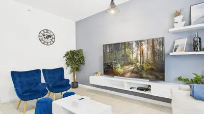 a living room with a flat screen tv and blue chairs at Spacious 2 BR with Sea and Marina View Bahar JBR in Dubai
