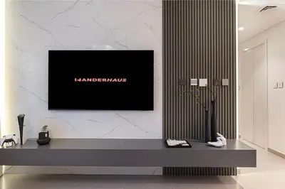 a living room with a television on a wall at Modern 2BR Apartments near Dubai Mall, Downtown in Dubai