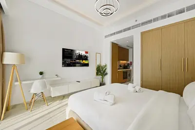 a white bedroom with a bed and a desk at Estudio Amira en Dubai by beBalmy in Dubai
