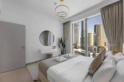 a bedroom with a large white bed with a large window at 2BR - Private Cinema - Pool - Walk to Burj Khalifa in Dubai