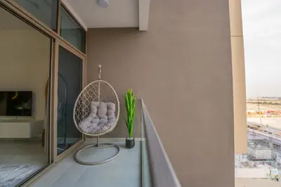 a wicker chair sitting on a balcony with a window at EasyGo - Chic Studio Escape in Dubai Sports City in Dubai