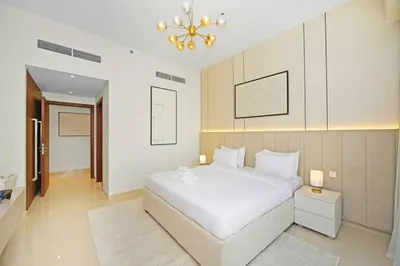 a bedroom with a white bed and a chandelier at Premium 2BR at Imperial Avenue overlooking Burj Khalifa in Dubai