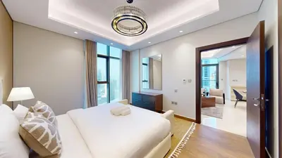a bedroom with a white bed and a living room at Vacationer l Modern 1 Bedroom l City Views l Prime Location in Dubai